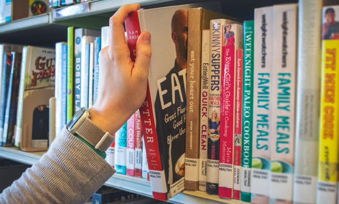 Someone pulling a book off of a shelf